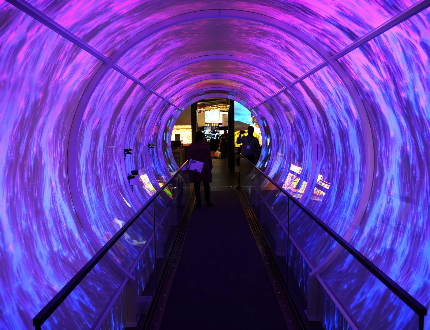 Visitors walking through a tunnel lined with projection